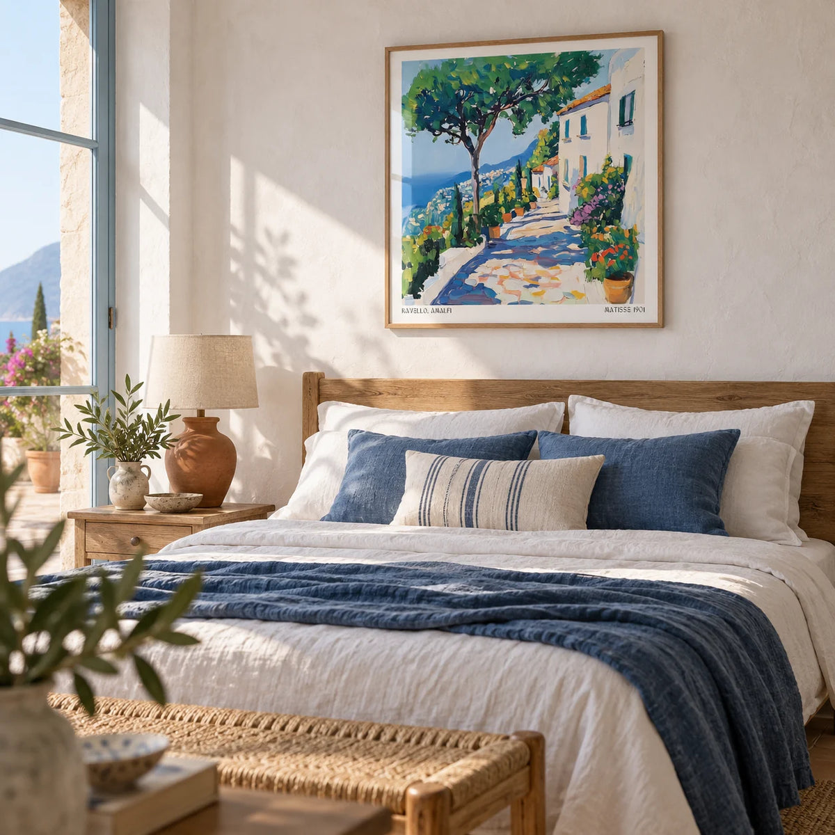 Prints of Amalfi Coast, framed on the wall of a calm Mediterranean bedroom with a limewashed white wall