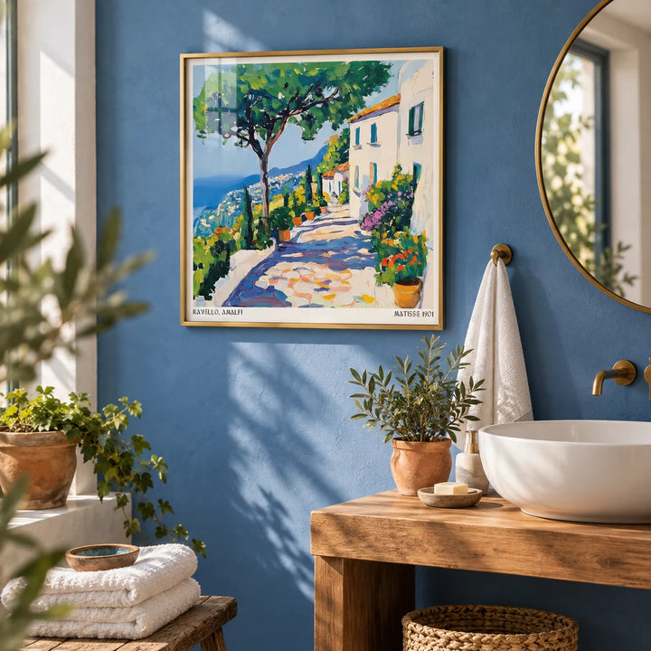 Prints of Amalfi Coast, framed on the wall of a fresh bathroom with a Mediterranean blue painted wall and a white basin on a wooden stand