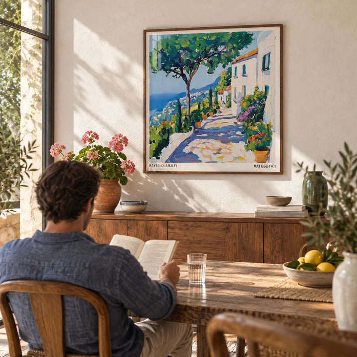 Prints of Amalfi Coast, framed on the wall of a sunny dining room with a warm white plaster wall
