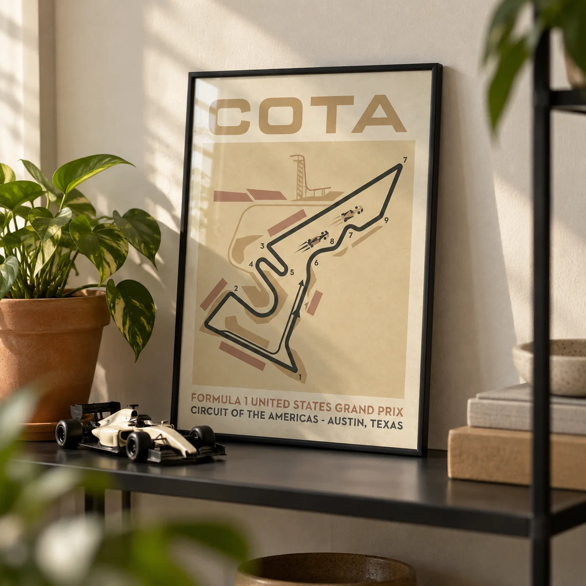 Race Track Map Poster, a small A4 framed print leaning on a black metal shelf in a living room