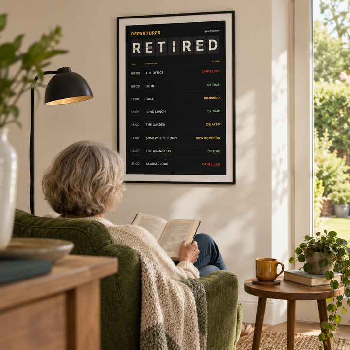 Retired Poster, framed on the wall of a bright modern reading corner in a retired adult's UK home with a cream wall and a garden-facing window in a living room