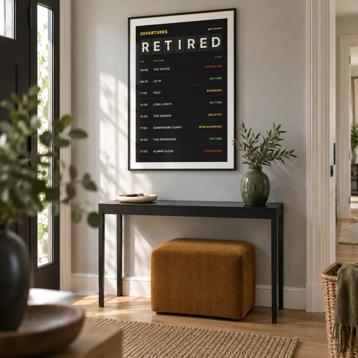 Retired Poster, framed on the wall of a contemporary entrance hallway in a retired couple's UK home with a pale grey wall and simple oak floorboards