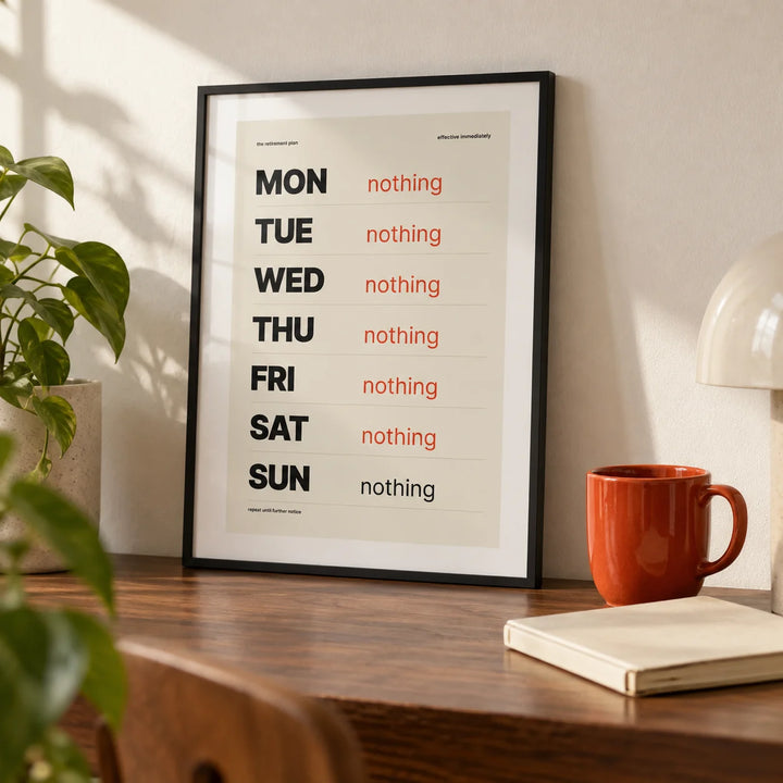 Retirement Plan Print, a small A4 framed print leaning on a walnut desk