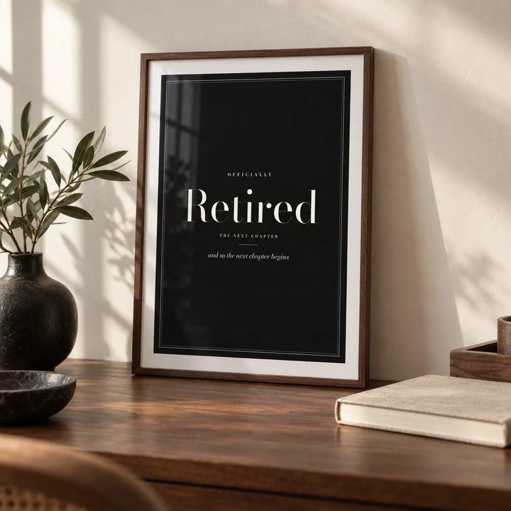 Retirement Poster, a small A4 framed print leaning on a walnut desk
