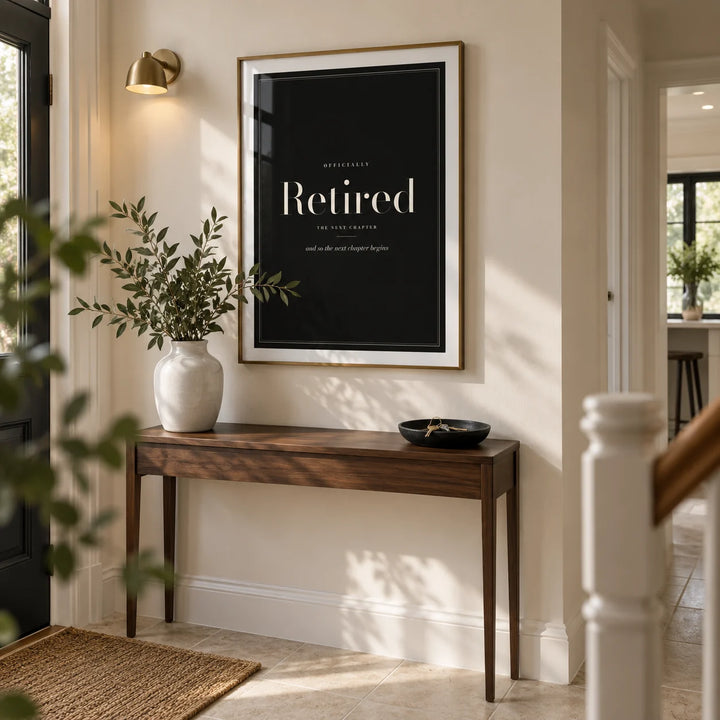 Retirement Poster, framed on the wall of a smart entrance hallway in a renovated UK semi-detached home with an ivory wall and pale stone floor
