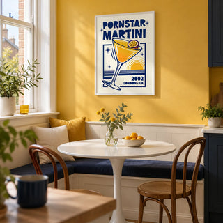 Retro Passion Fruit Martini Poster, framed on the wall of a compact kitchen breakfast nook in a converted UK flat with a solid muted golden yellow wall and a white pedestal table