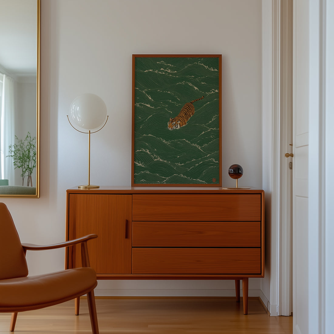 Green print of a tiger swimming through waves hung above a teak mid-century sideboard with a globe lamp