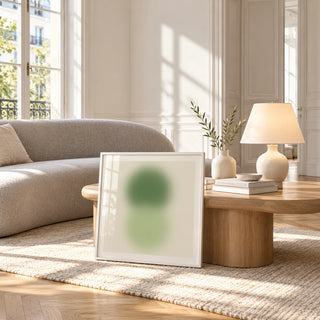Sage and Olive Print, framed and leaning against a coffee table in a bright living room