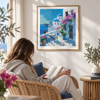 Santorini Wall Art Prints, framed on the wall of a breezy reading corner with a white wall in a living room