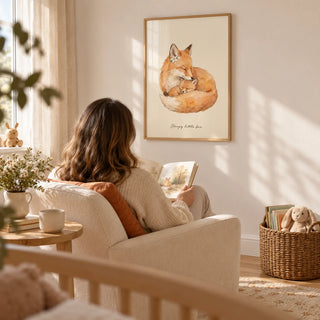 Sleepy Fox Art Print, framed on the wall of a quiet nursery reading corner with a warm white wall and light oak flooring