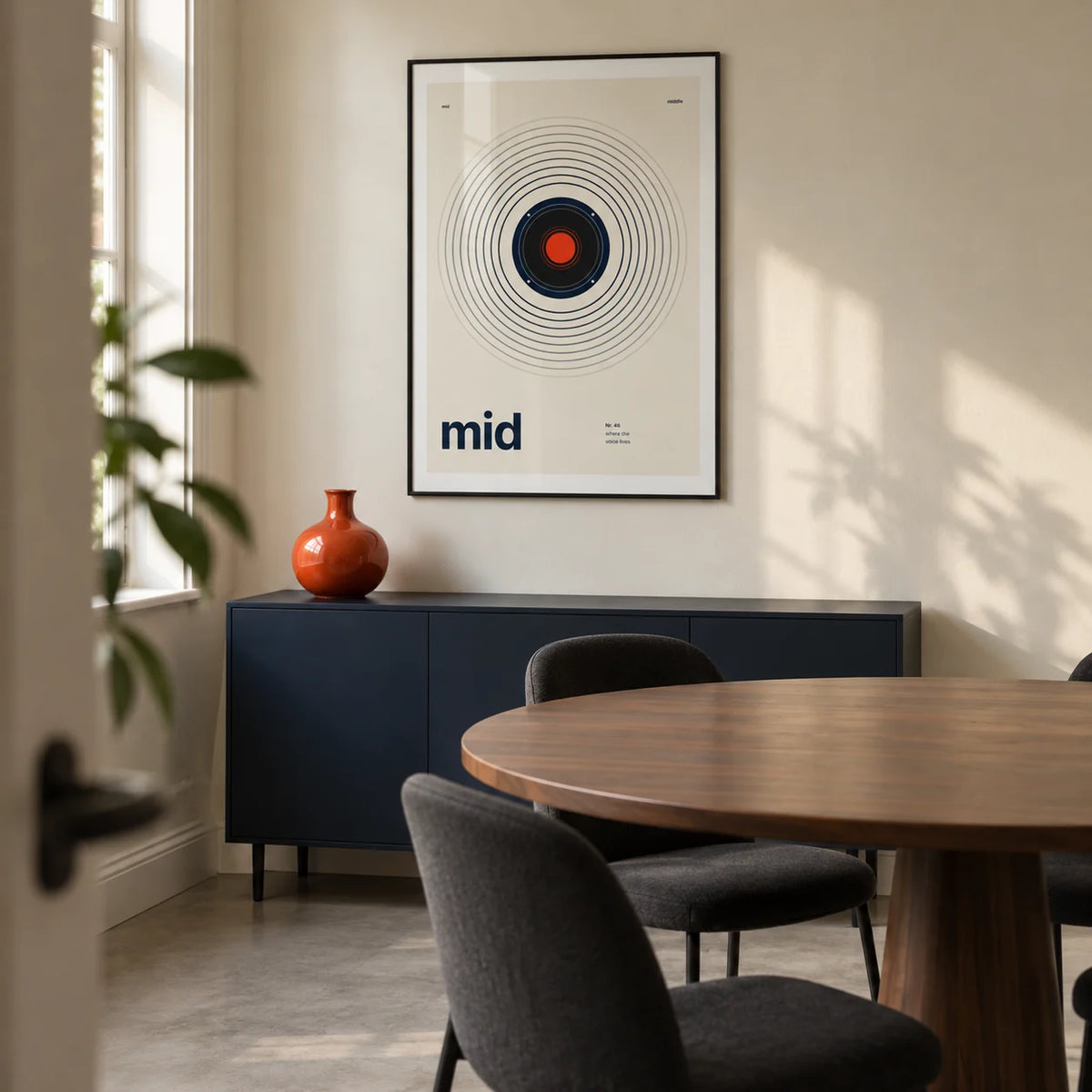 Speaker Poster, framed on the wall of a compact modern dining room in a UK terraced house with cream walls and a plain concrete floor