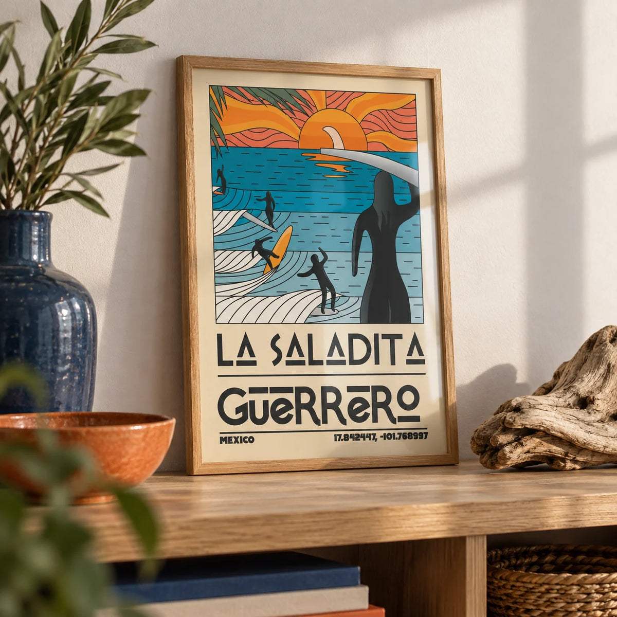 Surfing Sunset Print, a small A4 framed print leaning on an oak shelf in a living room