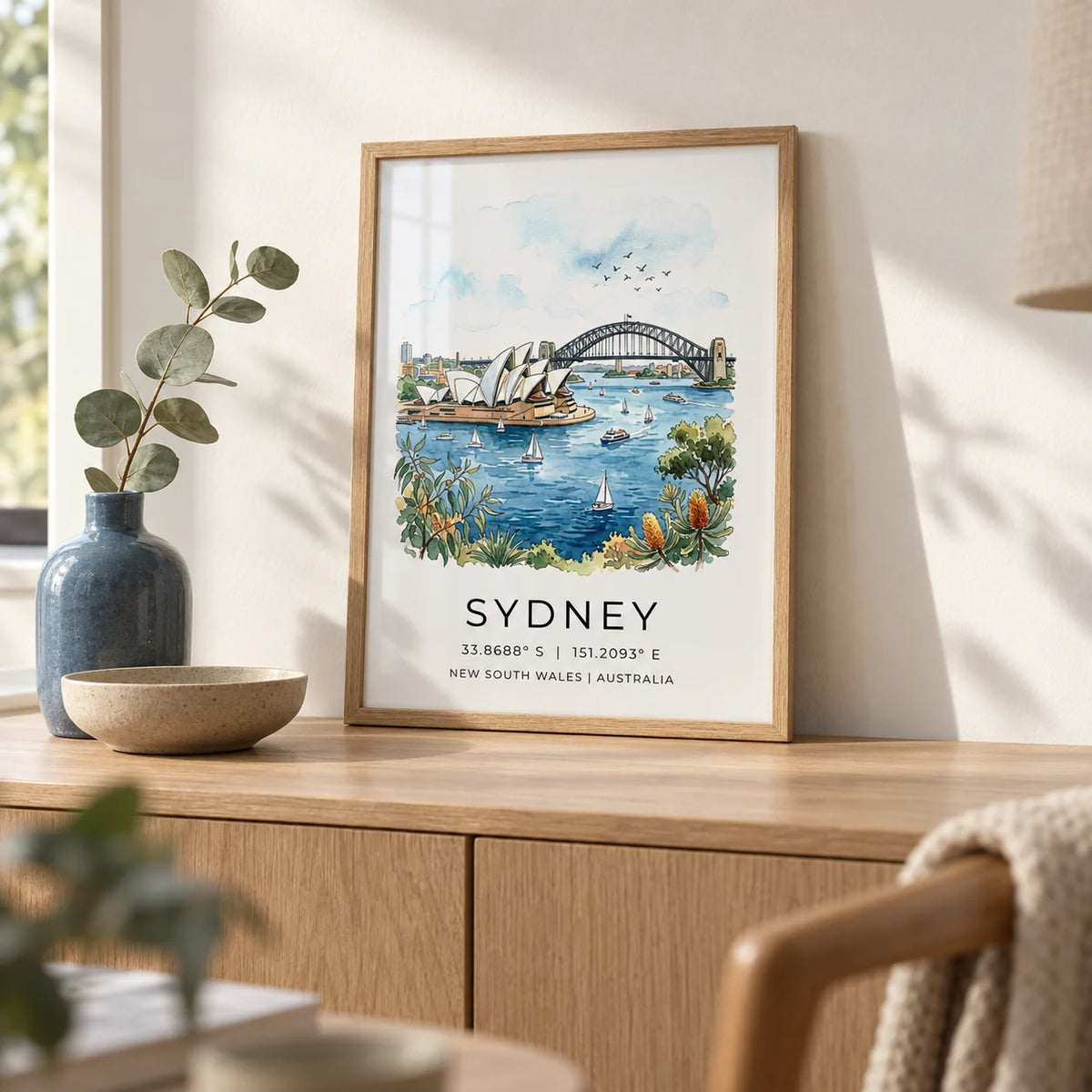 Sydney Watercolor Art Print, a small A4 framed print leaning on a pale oak sideboard in a living room