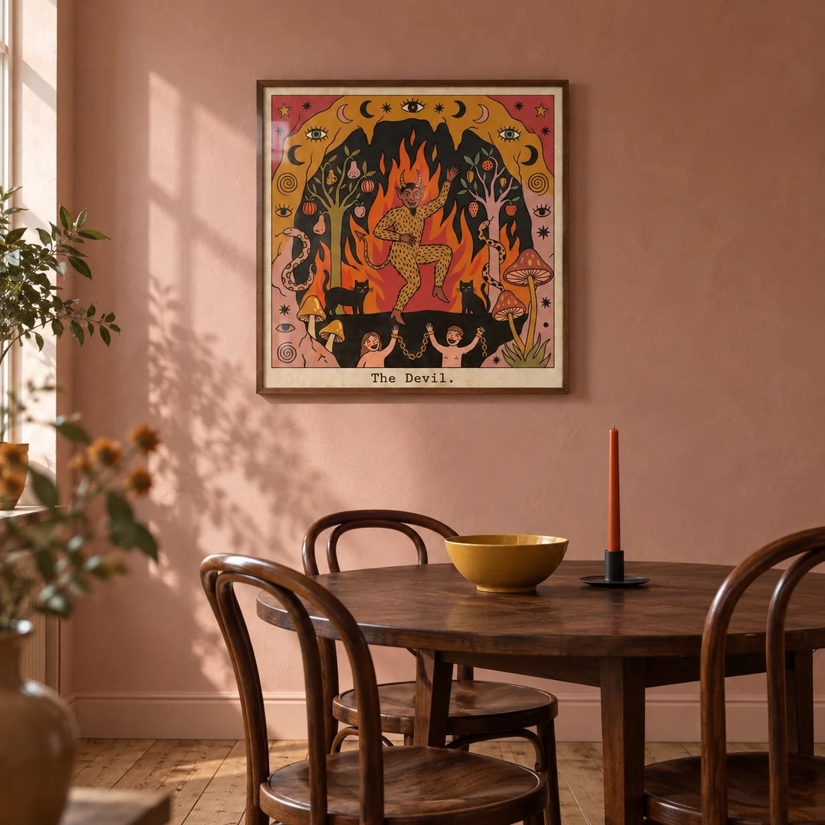 The Devil Tarot Card Art, framed on the wall of a warm dining room in a UK flat with muted dusty pink plaster walls and a plain timber floor