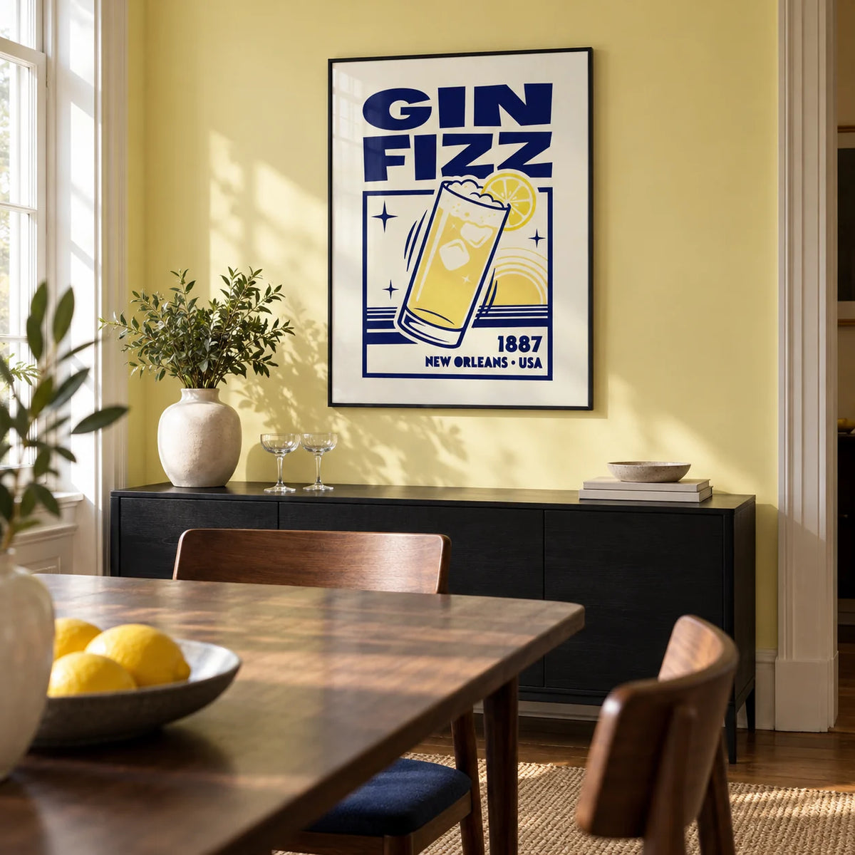Vintage Gin Fizz Print, framed on the wall of a design-led dining room in a UK townhouse with a muted lemon yellow wall and a dark wood dining table