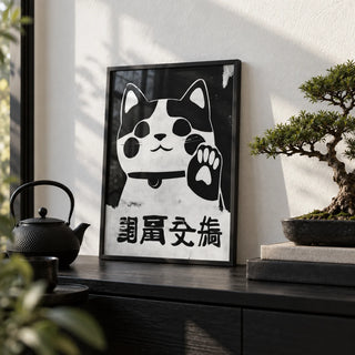 Waving Maneki Neko, a small A4 framed print leaning on a black shelf in a living room