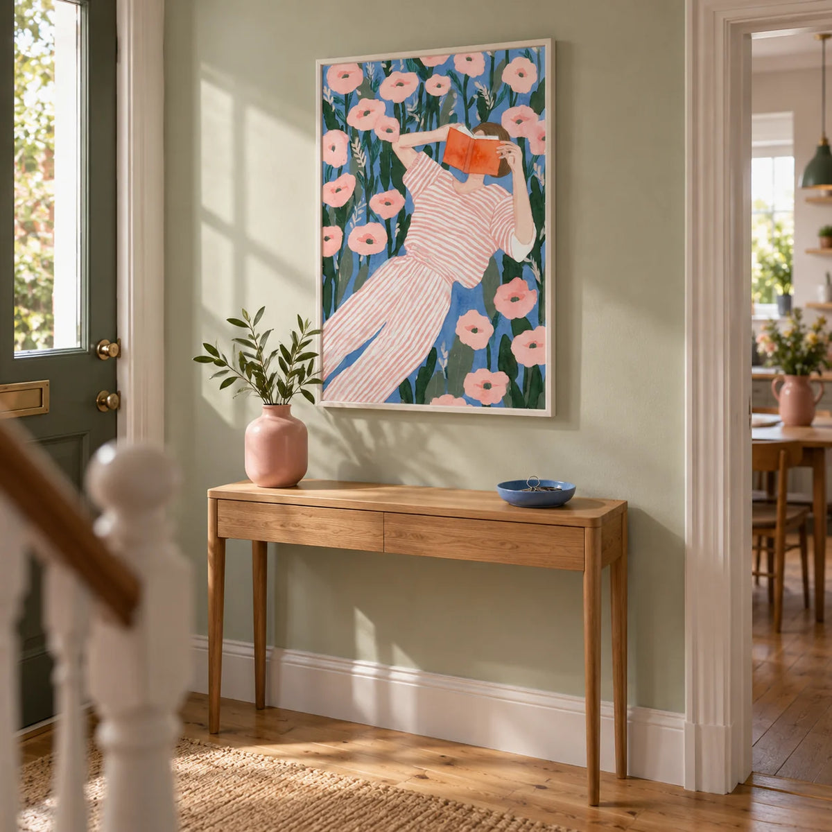 Woman Reading Art Print, framed on the wall of a welcoming hallway in a modest UK terrace with pale sage walls and natural oak floorboards