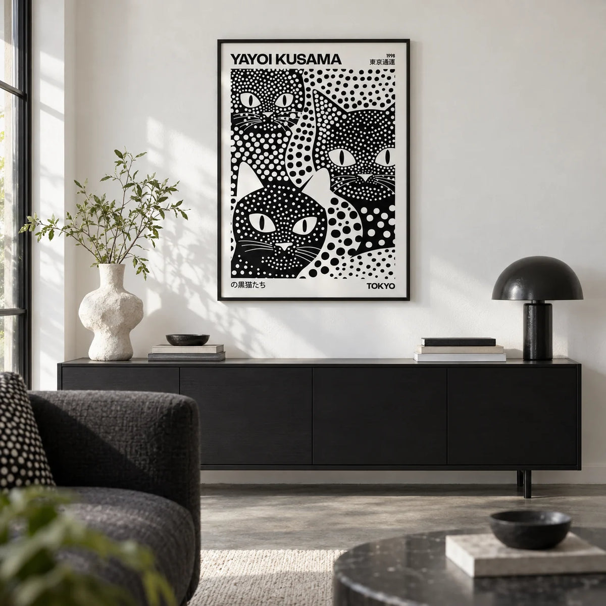Yayoi Kusama Black Cats, framed on the wall of a design-led city flat living room with a white wall and a polished concrete floor