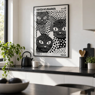 Yayoi Kusama Black Cats, framed on the wall of a modern white kitchen with a black worktop
