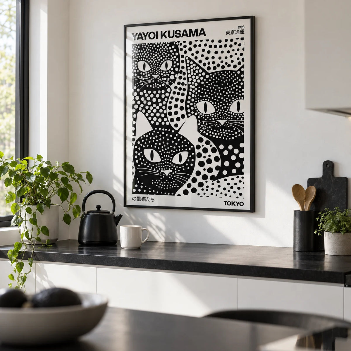 Yayoi Kusama Black Cats, framed on the wall of a modern white kitchen with a black worktop