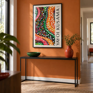 Yayoi Kusama Dots, framed on the wall of a modern hallway with an orange painted wall