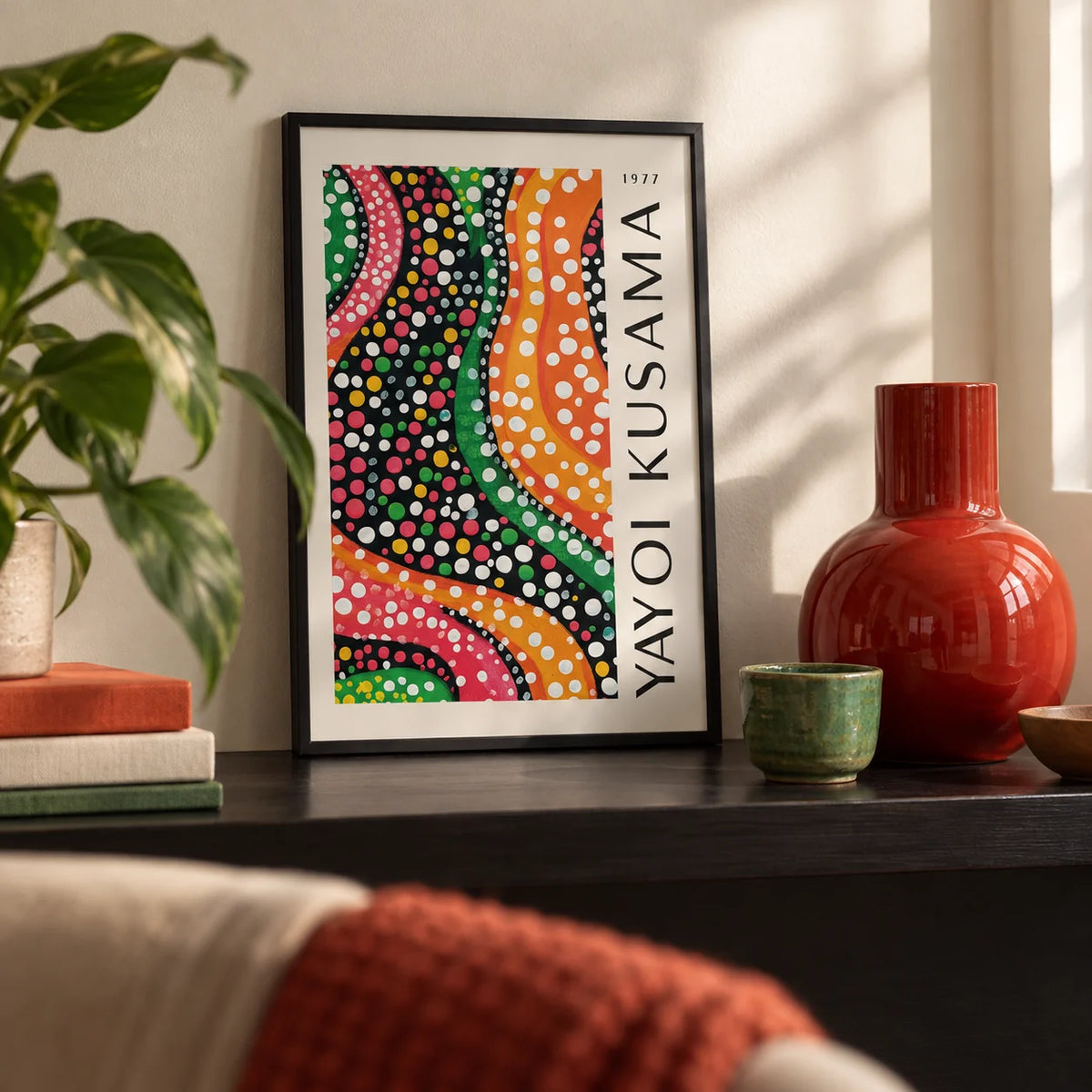Yayoi Kusama Dots, a small A4 framed print leaning on a black shelf in a living room