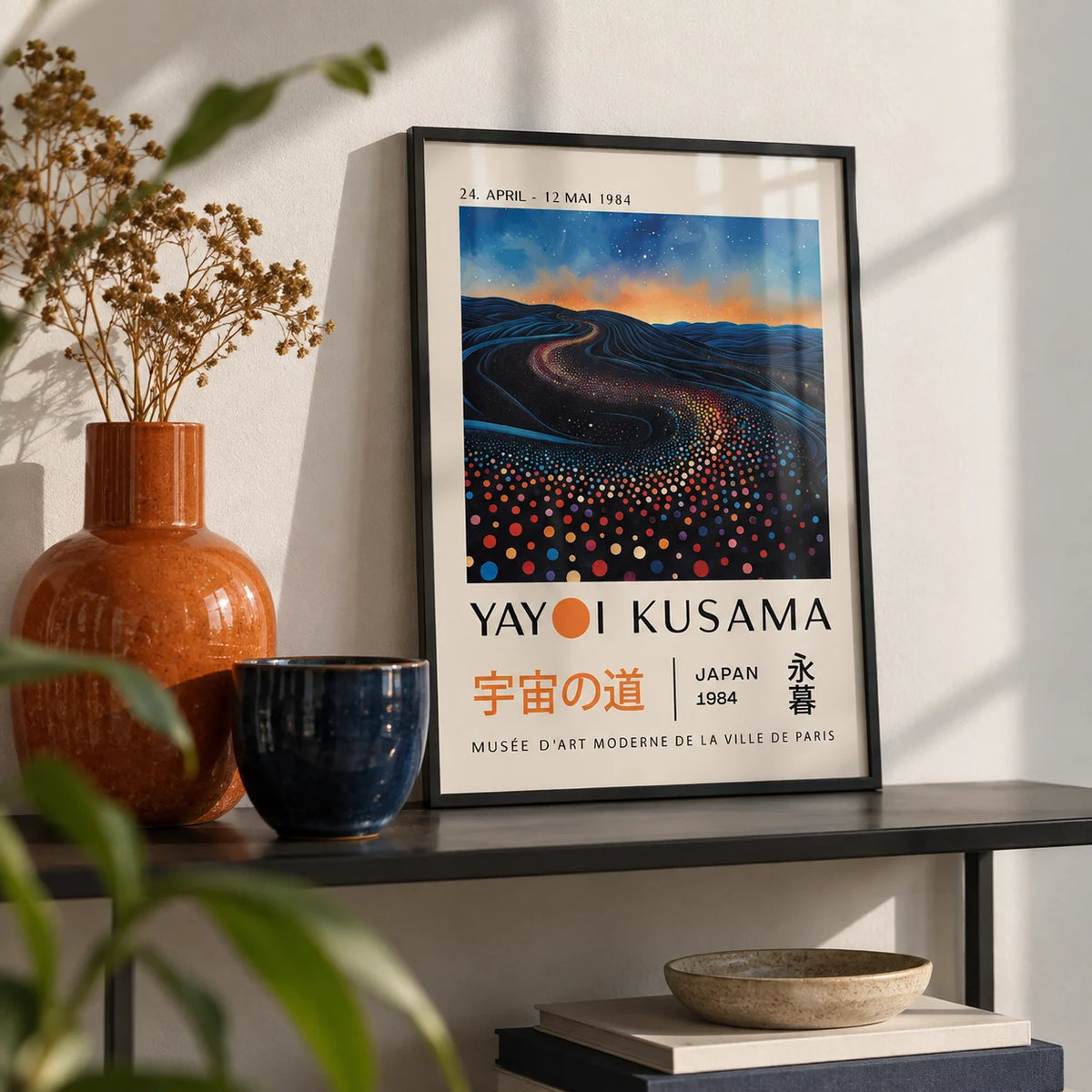 Yayoi Kusama Infinity Room Print, a small A4 framed print leaning on a black metal shelf in a living room