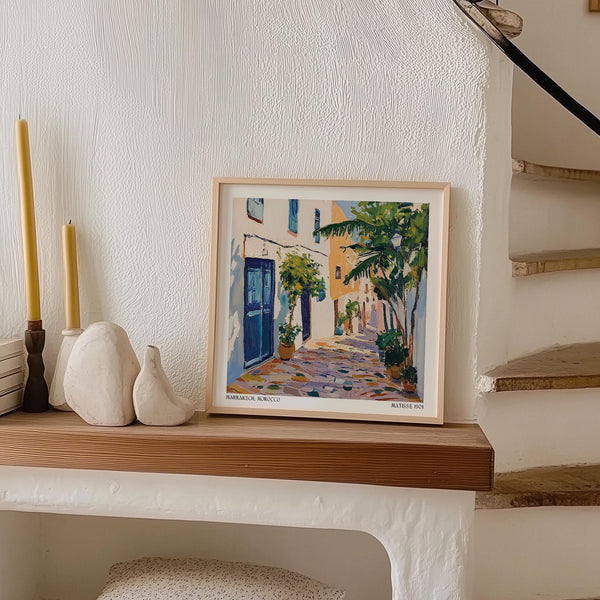 Art mural marocain représentant une ruelle tranquille avec des palmiers et des maisons aux volets fermés.