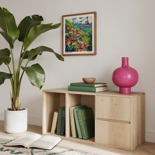 Étagère en bois avec des livres, un vase rose, une plante et des œuvres d'art colorées en arrière-plan.