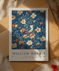 Œuvre de William Morris représentant un oiseau bleu parmi des fleurs abricot et crème, avec un feuillage bleu foncé.