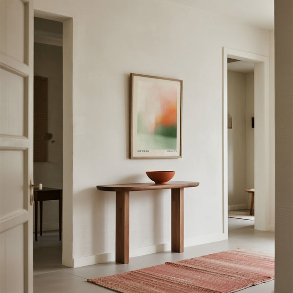 Consolle in legno con una ciotola e un quadro astratto in una stanza minimalista.