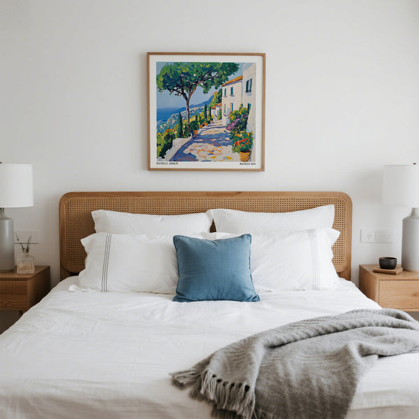 Stampe della Costiera Amalfitana in una camera da letto con letto con biancheria bianca e cuscino blu.