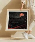 Terreno ondulato e luna rossa raffigurati in un'opera d'arte murale dall'atmosfera malinconica