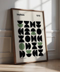 Stampa da galleria con audaci forme geometriche Bauhaus nere e verdi su sfondo color crema.